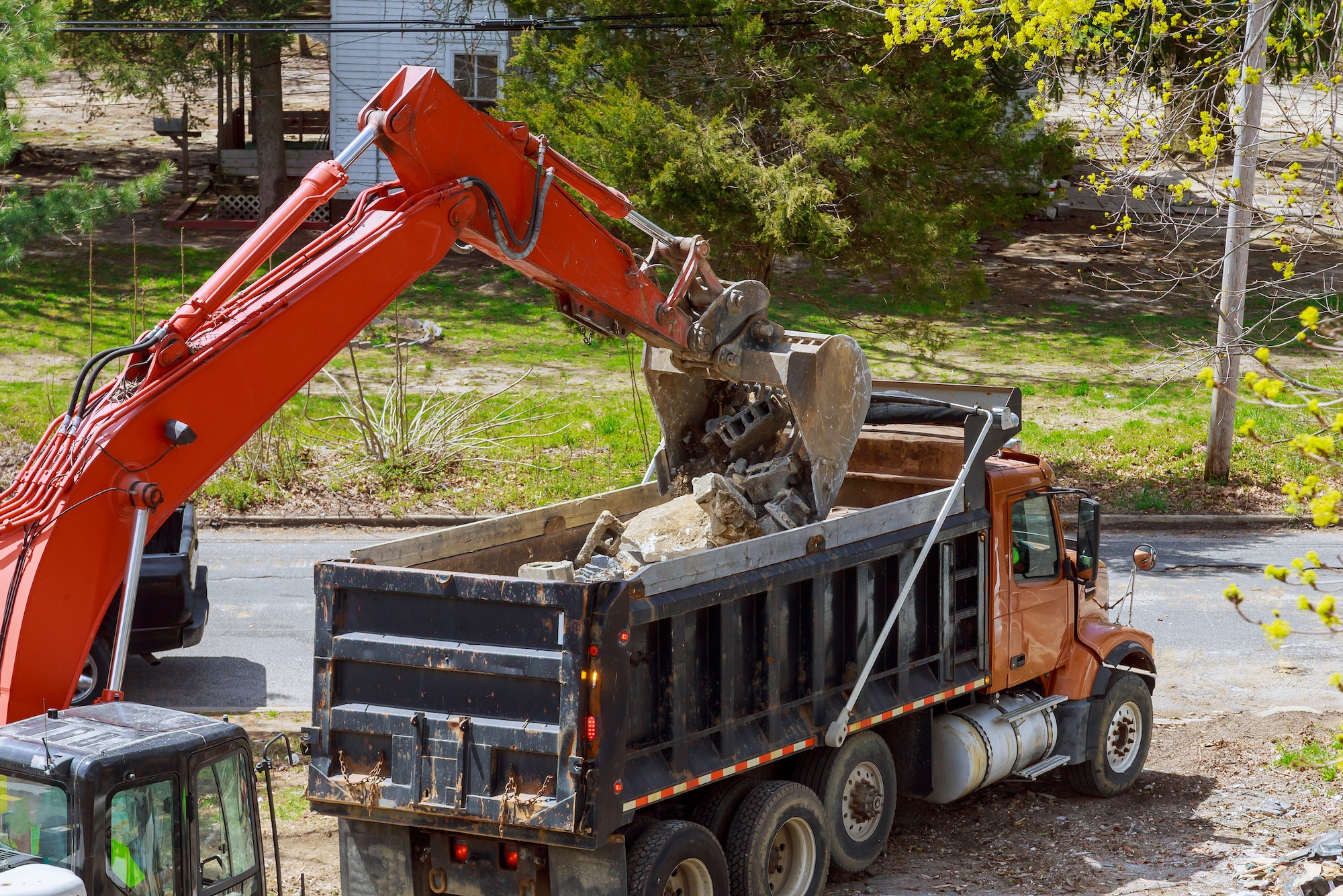 Truck with excavator loading for removal of debris construction waste building demolition