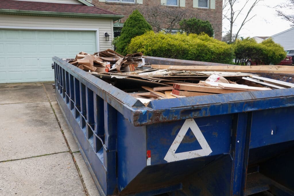 Long blue dumpster full of wood