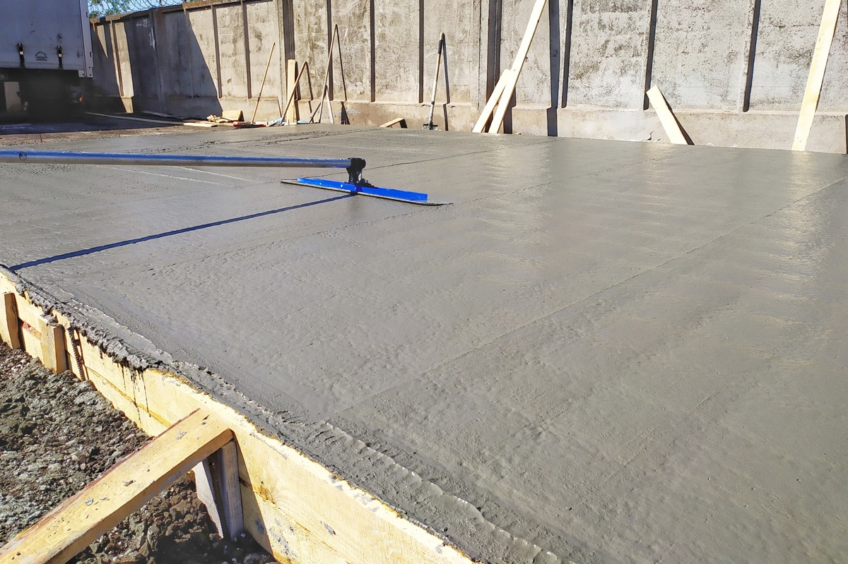 A wet concrete slab being smoothed out by a blue tool in El Paso.