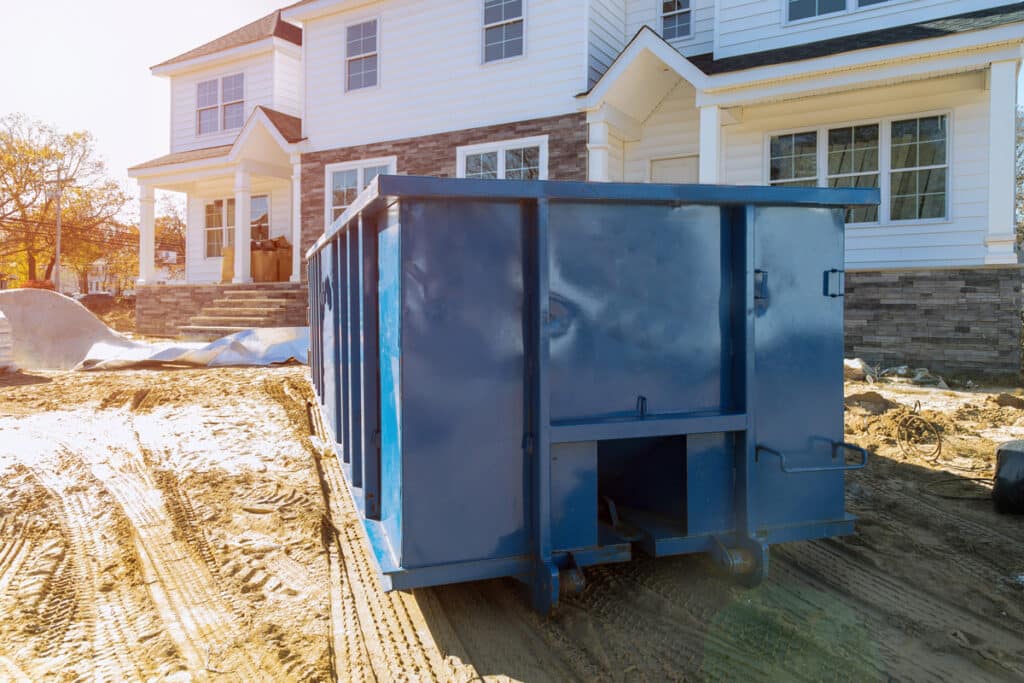 A large blue dumpster at a residential construction site in El Paso.